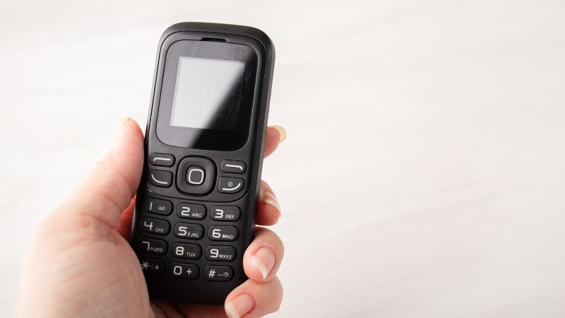 Close-up of a basic mobile phone being held in a person's hand, highlighting communication technology for voice calls.